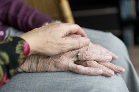 Junge Hand schützend auf alten Händen